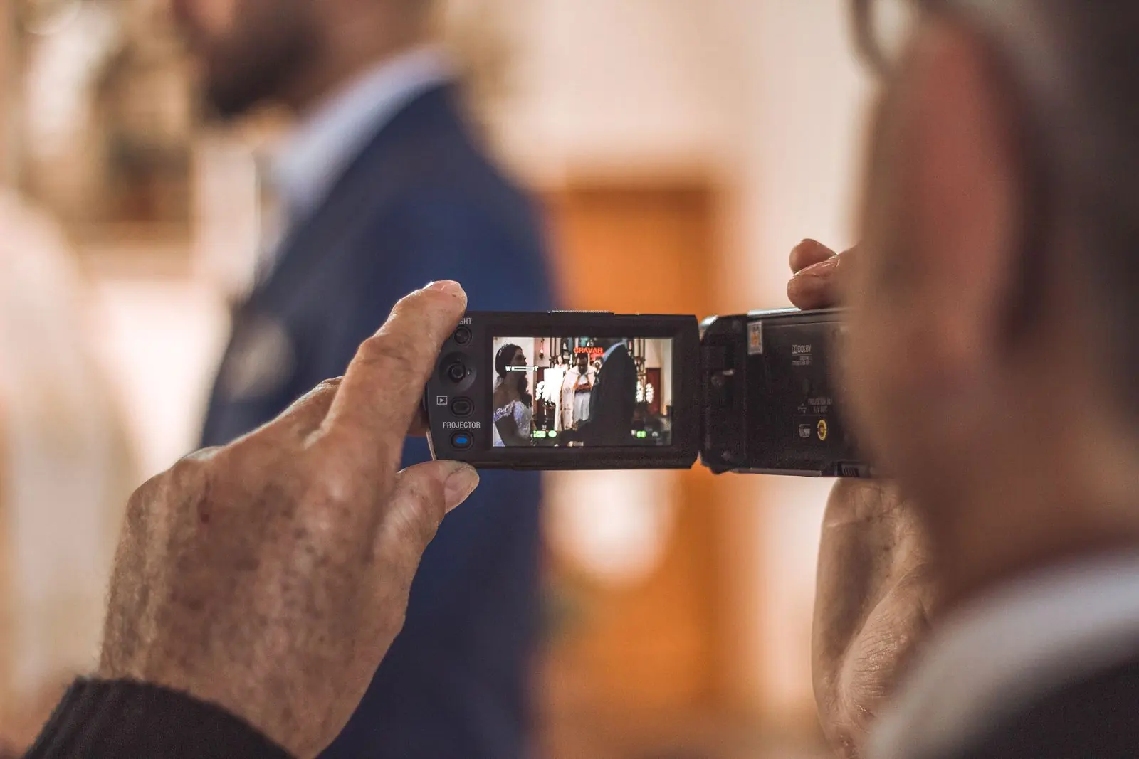 Des mains âgées filment un moment de famille avec un caméscope, photographie d’illustration.
