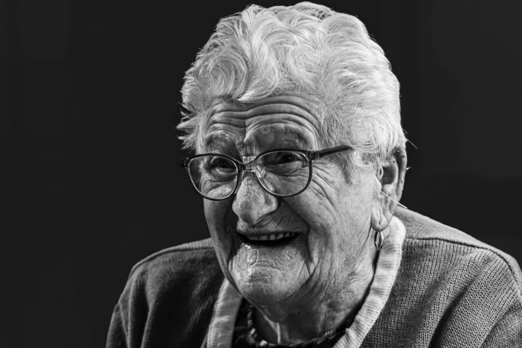Portrait en noir et blanc d’une femme âgée qui sourit, pour illustrer le film de vie